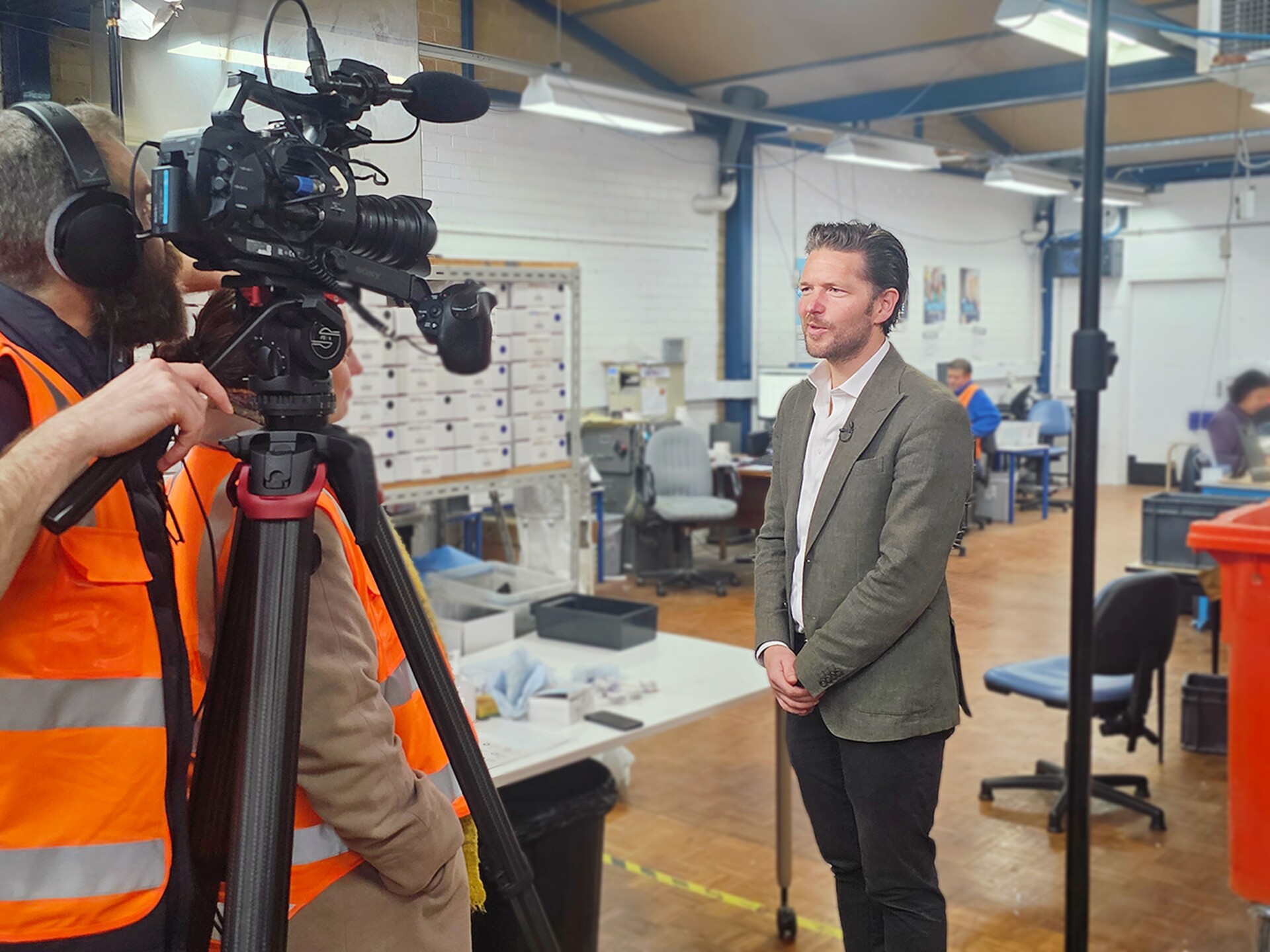 Sebastian from Transurban is standing in front of a camera, with the Ability Works mail room behind him