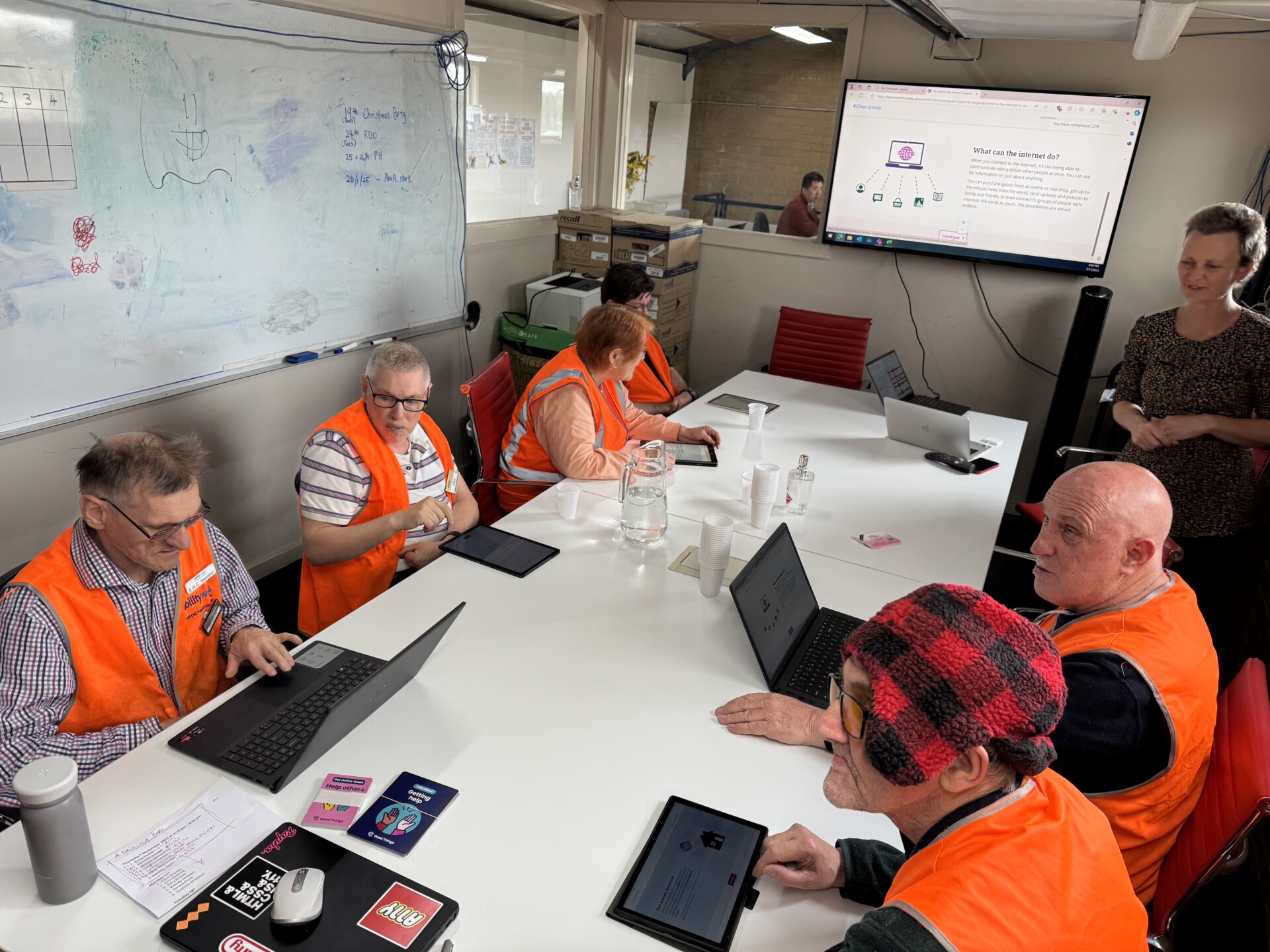 Ability Works employees are seated around the meeting table, participating in digital training